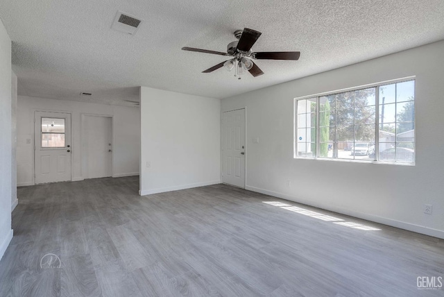 1857 Fern Tree Close, Wasco, CA 93280 - unfurnished living room with a textured ceiling, plenty of natural light, ceiling fan, and wood finished floors