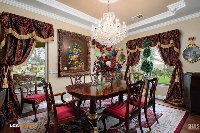 dining space with visible vents, wood finished floors, a tray ceiling, crown molding, and a notable chandelier