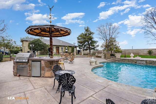 view of pool with a patio area, a grill, an outdoor bar, and area for grilling