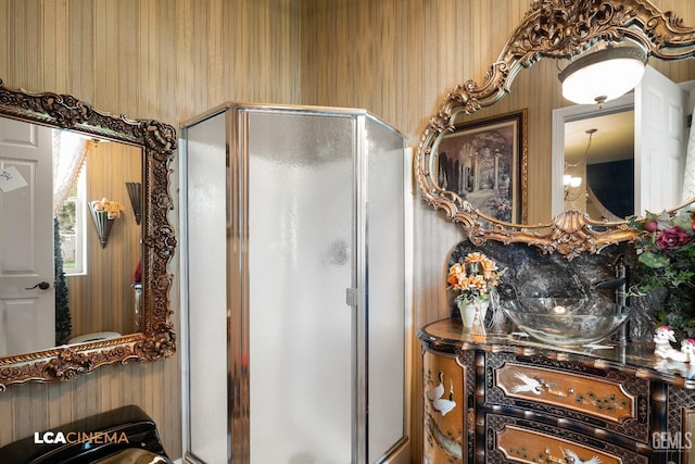 bathroom with a shower stall and an inviting chandelier