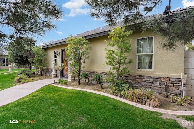 view of front facade featuring stone siding, a front lawn, and stucco siding