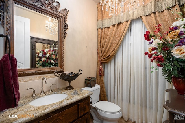 bathroom featuring tasteful backsplash, vanity, toilet, and a notable chandelier