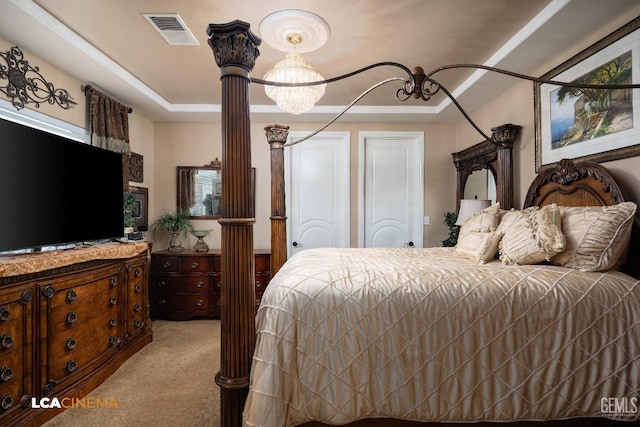 bedroom with light colored carpet, visible vents, a raised ceiling, decorative columns, and an inviting chandelier