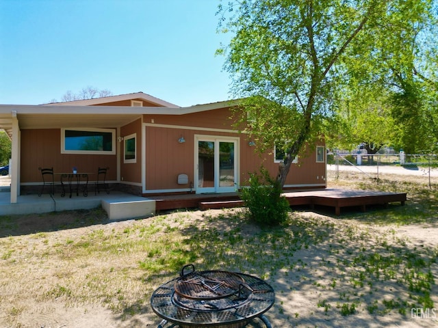 rear view of property featuring a fire pit and a wooden deck