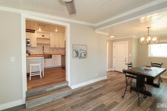 dining room with hardwood / wood-style flooring, sink, crown molding, and an inviting chandelier