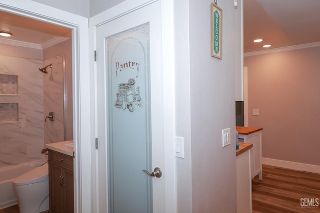 full bathroom with hardwood / wood-style floors, vanity, tiled shower / bath, toilet, and ornamental molding