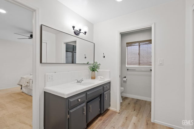 bathroom featuring hardwood / wood-style flooring, vanity, ceiling fan, and toilet