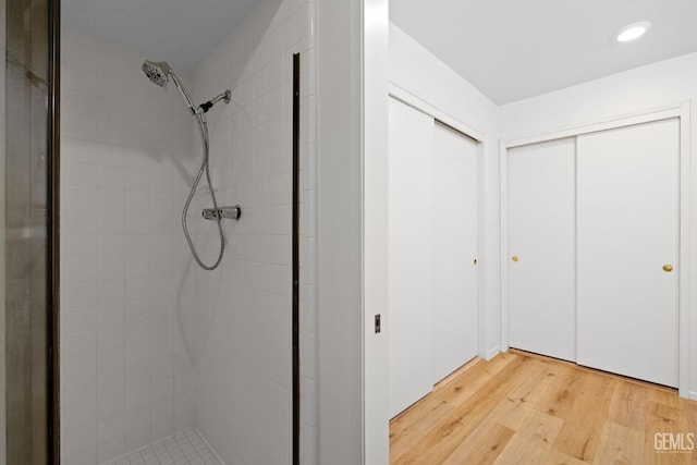 bathroom with wood-type flooring and tiled shower