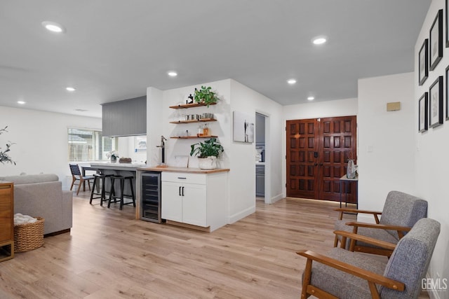 interior space with white cabinetry, beverage cooler, and light wood-type flooring