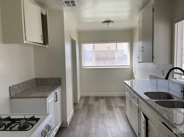 115 Olive St, Bakersfield, CA 93304 - kitchen featuring light wood-style floors, visible vents, light stone counters, a sink, and baseboards