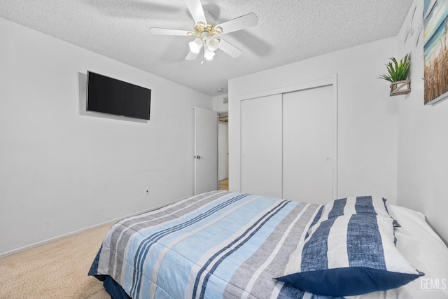 bedroom with ceiling fan, a closet, carpet, and a textured ceiling