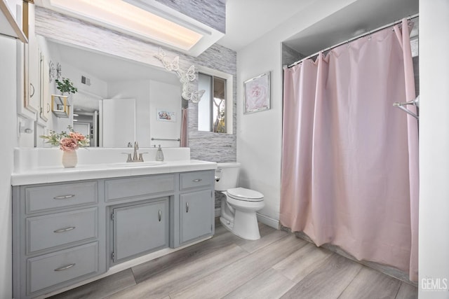 bathroom featuring wood-type flooring, vanity, toilet, and walk in shower