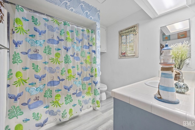 bathroom featuring hardwood / wood-style floors, vanity, toilet, and curtained shower