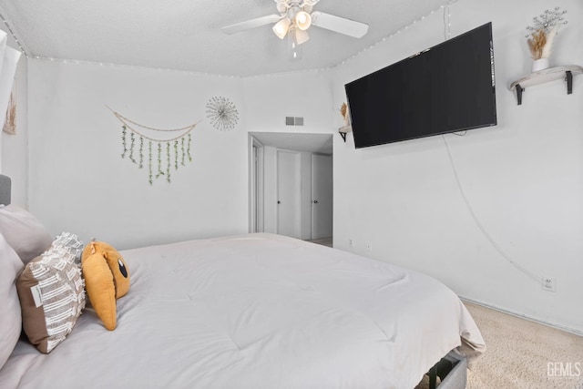 carpeted bedroom with ceiling fan and a textured ceiling