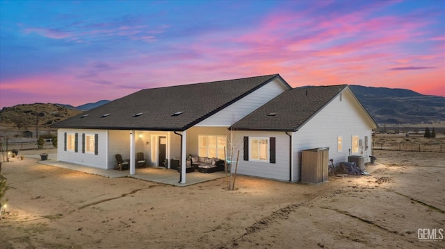 back house at dusk with a mountain view, a patio area, and central AC unit