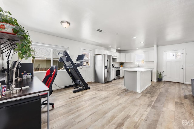 kitchen featuring a center island, light countertops, appliances with stainless steel finishes, light wood-style floors, and white cabinetry