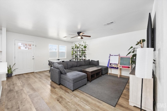 living area featuring light wood finished floors, baseboards, a ceiling fan, and visible vents