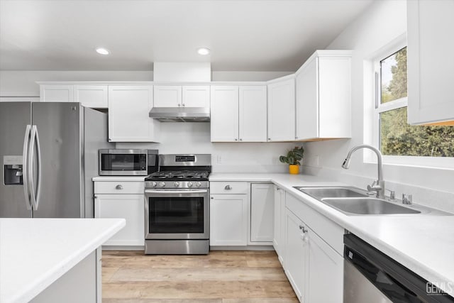 kitchen featuring white cabinetry, appliances with stainless steel finishes, under cabinet range hood, light countertops, and a sink