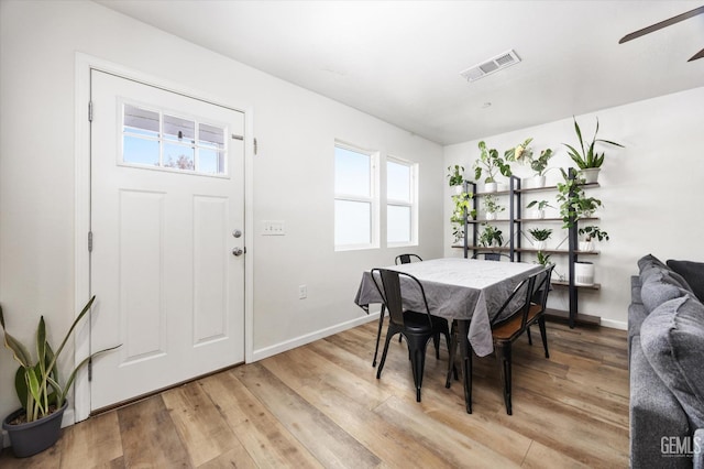 dining area featuring light wood-style flooring, ceiling fan, baseboards, and visible vents