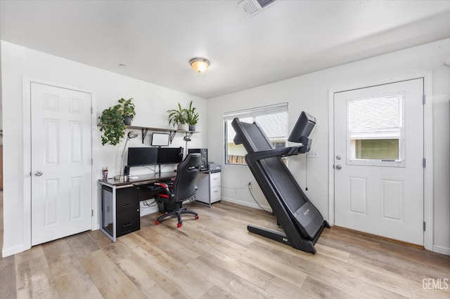 home office with visible vents, baseboards, light wood-type flooring, and a healthy amount of sunlight
