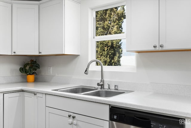 kitchen with a sink, light countertops, stainless steel dishwasher, and white cabinets