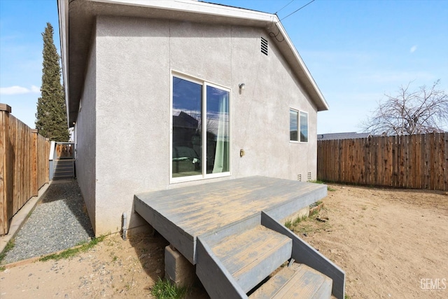 back of property featuring a deck, stucco siding, and a fenced backyard