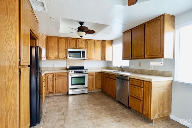 kitchen with visible vents, ceiling fan, tile counters, appliances with stainless steel finishes, and a sink