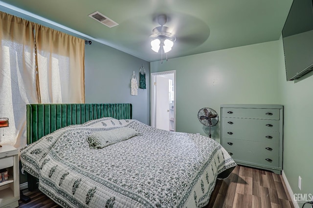 bedroom with dark hardwood / wood-style flooring, ensuite bathroom, and ceiling fan