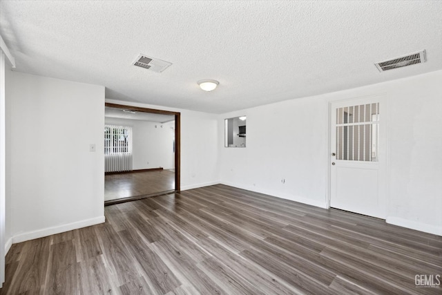 unfurnished room featuring dark hardwood / wood-style flooring and a textured ceiling