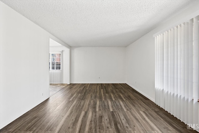 empty room with dark wood-type flooring and a textured ceiling