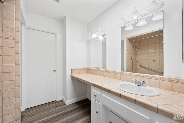 bathroom with backsplash, vanity, wood-type flooring, and tiled shower