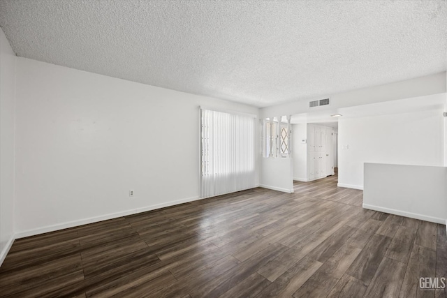 empty room with dark hardwood / wood-style flooring and a textured ceiling