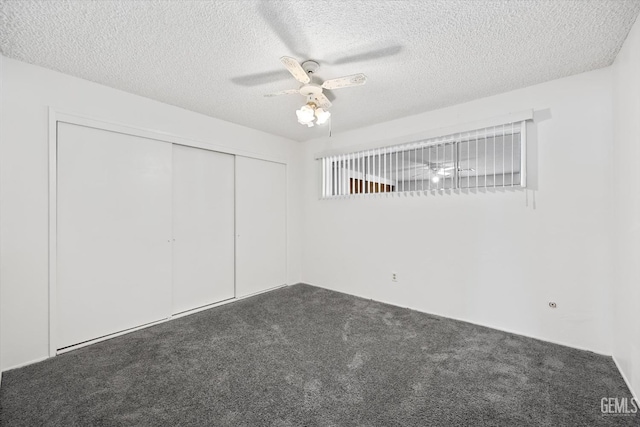 unfurnished bedroom featuring dark colored carpet, a closet, and ceiling fan