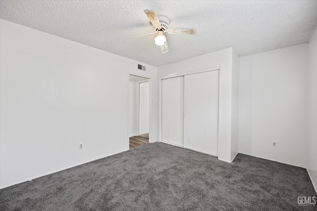 unfurnished bedroom featuring ceiling fan, a closet, dark carpet, and a textured ceiling