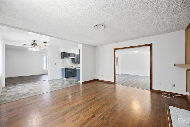 unfurnished living room featuring a textured ceiling, dark hardwood / wood-style flooring, and ceiling fan