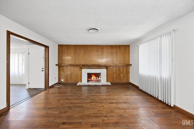 unfurnished living room featuring a fireplace, a textured ceiling, and dark wood-type flooring