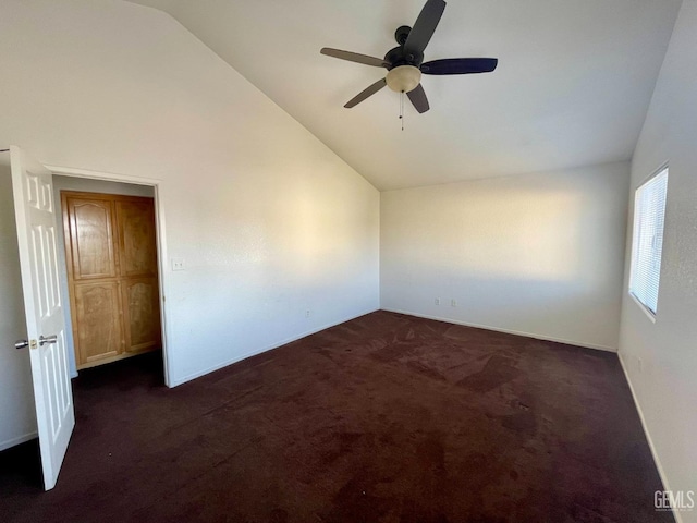 unfurnished room with ceiling fan, baseboards, dark colored carpet, and vaulted ceiling