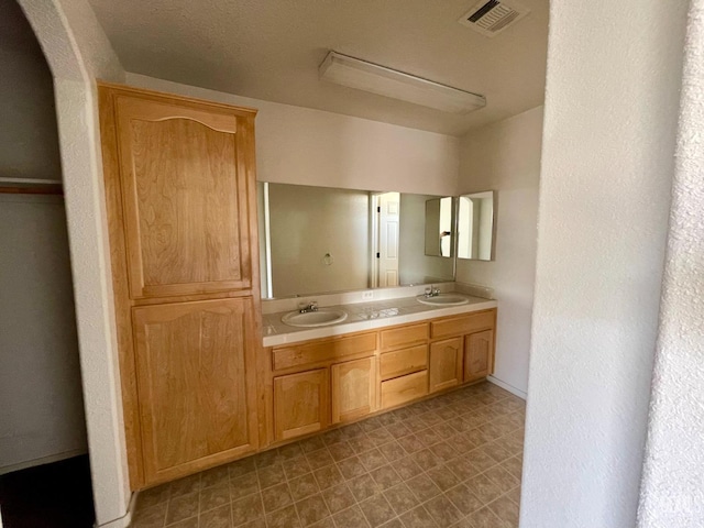 bathroom with double vanity, visible vents, tile patterned floors, and a sink