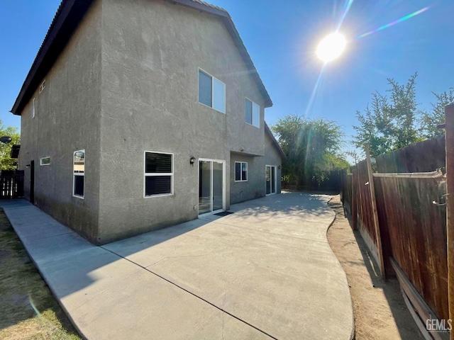 rear view of house with a patio area, a fenced backyard, and stucco siding