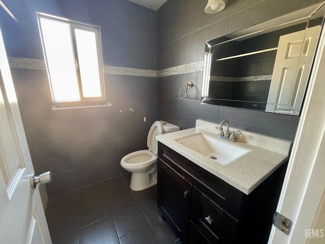 bathroom with tile patterned floors, toilet, tile walls, and vanity