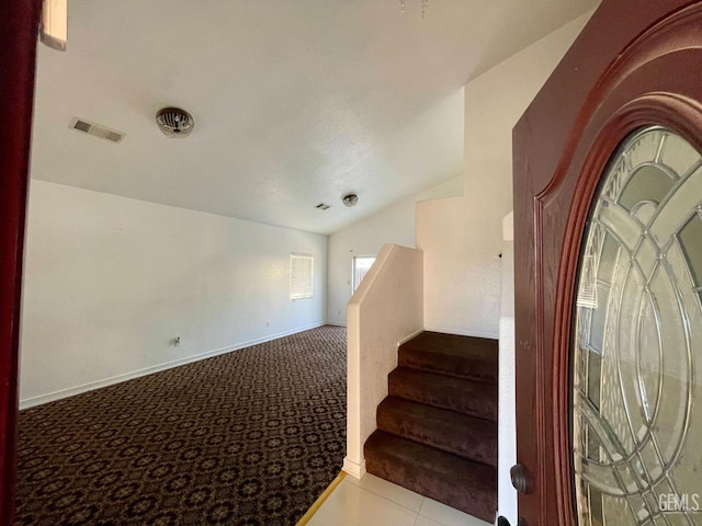 staircase featuring visible vents, baseboards, carpet, tile patterned flooring, and lofted ceiling