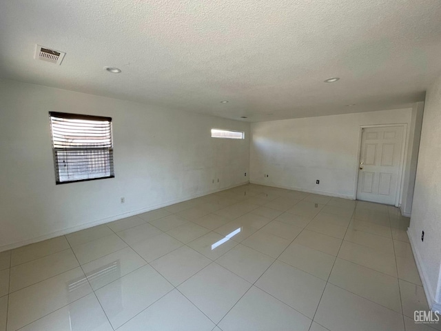 unfurnished room featuring light tile patterned floors, visible vents, and a textured ceiling