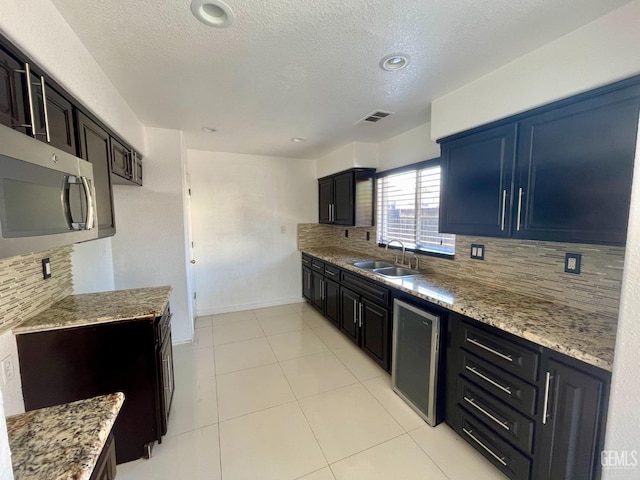 kitchen with baseboards, visible vents, a sink, decorative backsplash, and stainless steel microwave