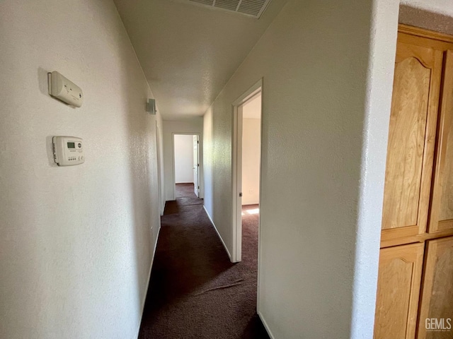 hallway with visible vents and dark colored carpet