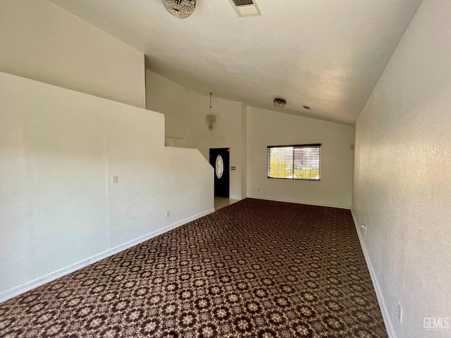 unfurnished room with visible vents, a textured ceiling, carpet floors, baseboards, and vaulted ceiling