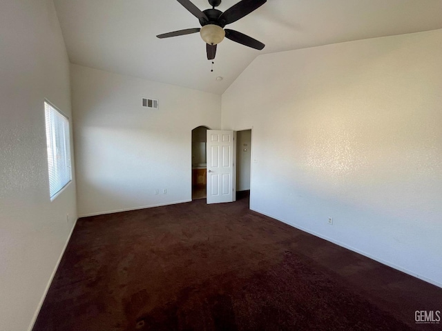 unfurnished room featuring visible vents, baseboards, arched walkways, high vaulted ceiling, and dark colored carpet