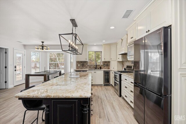 7544 Clifford Ct, Bakersfield, CA 93313 - kitchen with appliances with stainless steel finishes, a chandelier, a sink, wine cooler, and decorative backsplash