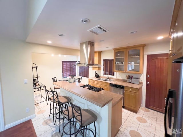 kitchen featuring appliances with stainless steel finishes, sink, island exhaust hood, and a breakfast bar area