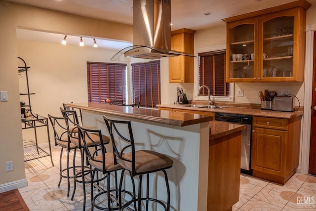 kitchen featuring kitchen peninsula, island range hood, sink, dishwasher, and a breakfast bar area