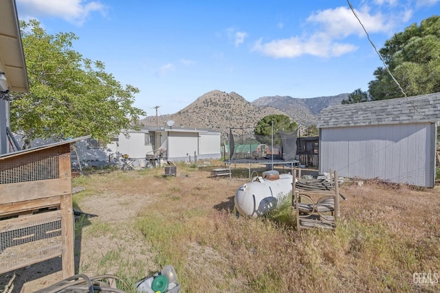 7958 Harmony Ln, Onyx, CA 93255 - view of yard featuring a trampoline, a storage unit, an outbuilding, and a mountain view